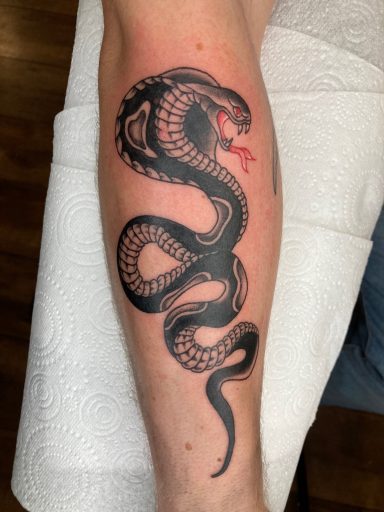 Tattoo of a coiled snake on a forearm, with a striking red tongue.
