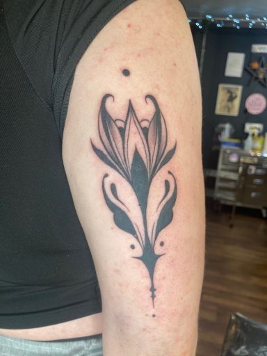 Black floral tattoo design on the upper arm with intricate detailing.